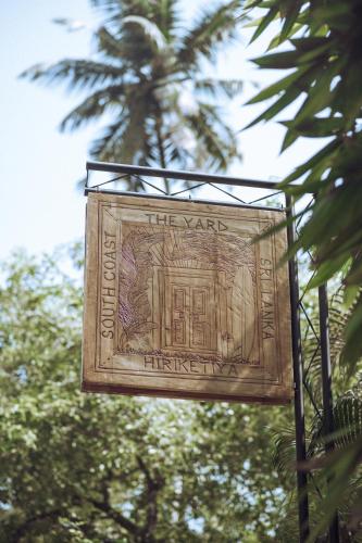um sinal está pendurado em frente a uma palmeira em The Yard Hiriketiya em Hiriketiya
