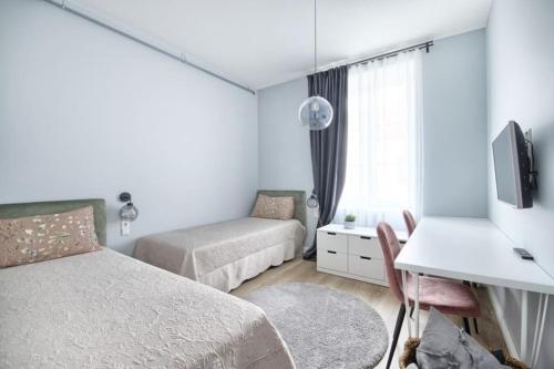 sypialnia z 2 łóżkami, biurkiem i telewizorem w obiekcie Cosy 3 room apartment. w Wilnie