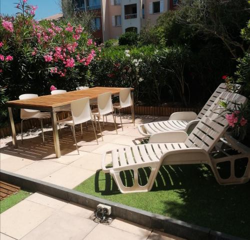 a wooden table and chairs and a wooden table and chairs at Appartement Zen à Frejus avec jardin, piscine, tennis, proche mer in Fréjus