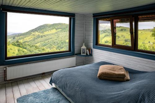 a bedroom with a bed and two large windows at Cabana Misha in Băişoara