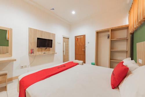 a bedroom with a large white bed with red pillows at RedDoorz Syariah near Taman Bekapai 2 in Klandasan Kecil