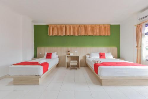 1 Schlafzimmer mit 2 Betten und einer grünen Wand in der Unterkunft RedDoorz Syariah near Taman Bekapai 2 in Klandasan Kecil