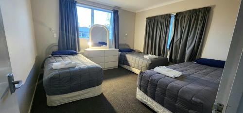 a hotel room with two beds and a mirror at Acorn Estate Motel in Masterton