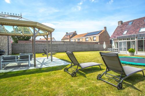 a yard with two chairs and a pool at Villa Maison Remi - 12 pers & hotspa in the garden in Koksijde