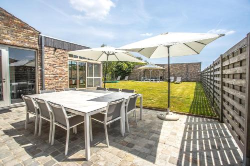 a patio with a white table and two umbrellas at Villa Maison Remi - 12 pers & hotspa in the garden in Koksijde