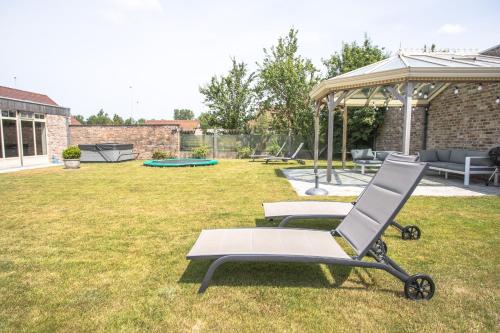 a chair and a table in a yard at Villa Maison Remi - 12 pers & hotspa in the garden in Koksijde