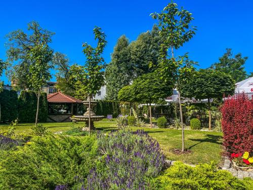 a garden with flowers and trees on a sunny day at Hotel Adria in Ruda Śląska