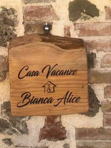 a wooden sign hanging on a brick wall at Casa Vacanze Bianca Alice in Catabbio