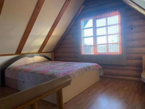 a bedroom with a bed and a window in a attic at Poilsis ant Virintų ežero kranto in Molėtai