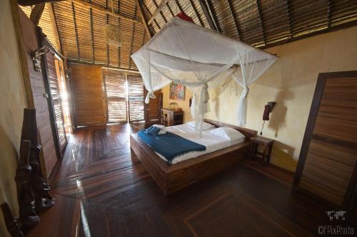 - une chambre avec un lit à baldaquin dans l'établissement Nosy Komba Lodge, à Nosy Komba