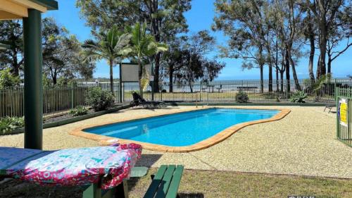 a swimming pool with a bench in front of it at San Marco Villa Close To Beach in Burrum Heads