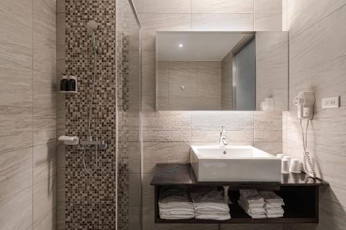 a bathroom with a sink and a shower with a mirror at Hotel Yoshi in Kaohsiung