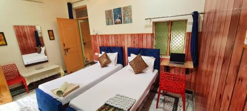 Habitación con 2 camas y escritorio con ordenador portátil. en Anukampa Paying Guest House en Agra