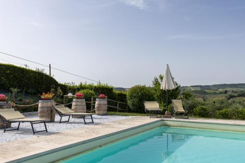 a swimming pool with chaises and chairs next to a house at Suite Cantina in San Gimignano