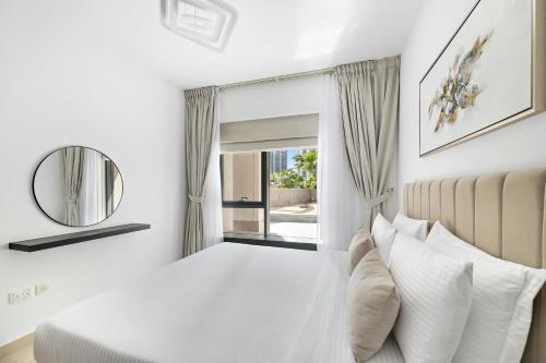 a white bedroom with a bed and a mirror at Designer 1BR 29 Boulevard Downtown Dubai Near Burj Khalifa in Dubai