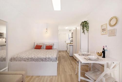 a white bedroom with a bed and a table at Estudio Torres del Sol in Playa de las Americas