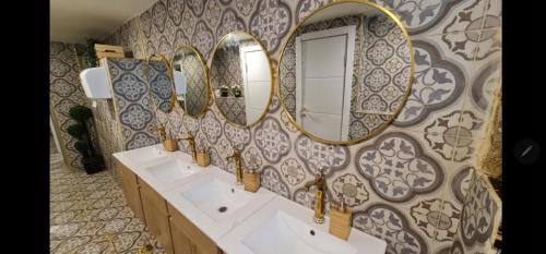 La salle de bains est pourvue de 3 lavabos et de miroirs sur un mur. dans l'établissement CAPSULES & Dormitory BH, à Jérusalem