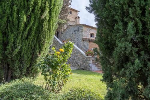 an old building is seen between two large trees at Suite Orcio in San Gimignano