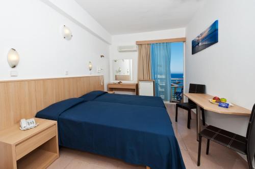 Pokój hotelowy z niebieskim łóżkiem i biurkiem w obiekcie Europa Hotel w mieście Rodos