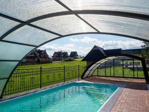 a swimming pool under an archway with a fence at Folk Resort Domki i Apartamenty in Murzasichle