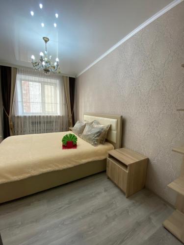 Schlafzimmer mit einem Bett und einem Kronleuchter in der Unterkunft VIP квартира в Центре, 2 комнаты in Qostanai