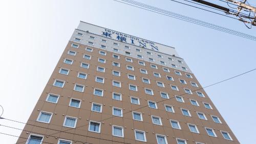 a tall building with a sign on top of it at Toyoko Inn Tsu eki Nishi guchi in Tsu