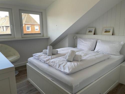 ein großes weißes Bett in einem Zimmer mit zwei Kissen in der Unterkunft Ferienwohnung Dünenblick in Westerland