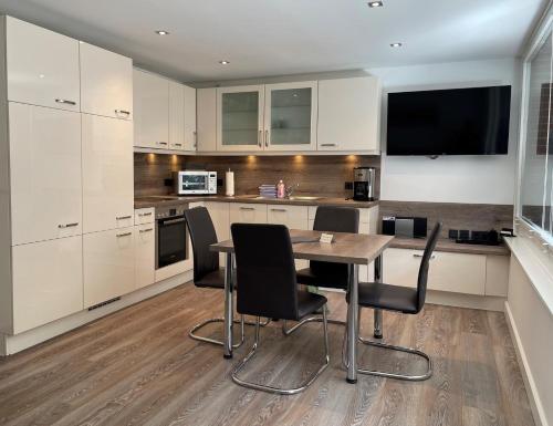 eine Küche mit weißen Schränken sowie einem Holztisch und Stühlen in der Unterkunft Ferienwohnung Dünenblick in Westerland