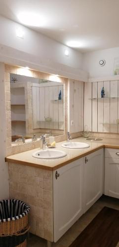 une salle de bain avec deux lavabos et deux miroirs dans l'établissement Charmante maison atypique à l'abri des regards, à Saint-Victor-la-Coste