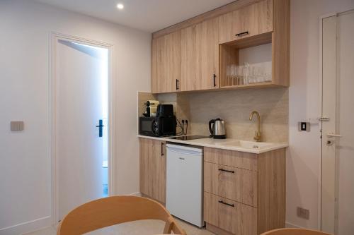 a small kitchen with wooden cabinets and a sink at Superbe studio avec balcon vue mer à 100m de la plage in Saint-Tropez