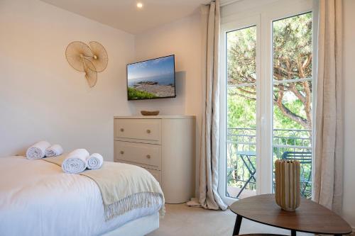 a white bedroom with a bed and a window at Superbe studio avec balcon vue mer à 100m de la plage in Saint-Tropez