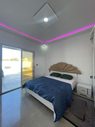 1 dormitorio con 1 cama con luz morada encima en Diar ayat V1, en Taguermess