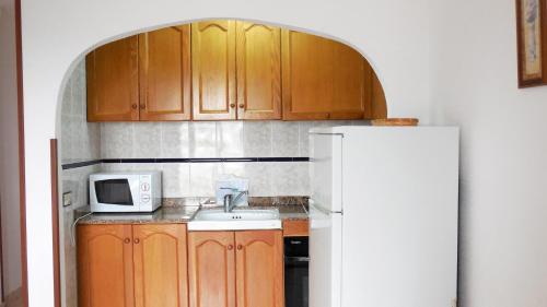 a kitchen with wooden cabinets and a white refrigerator at Apartamentos Costa Azahar 3000 in Alcossebre