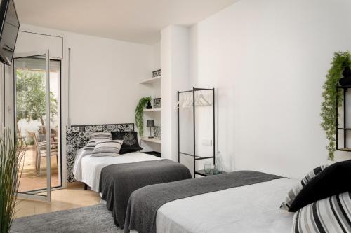 Habitación blanca con 4 camas y espejo. en Carme -Alojamiento céntrico en Girona, en Girona