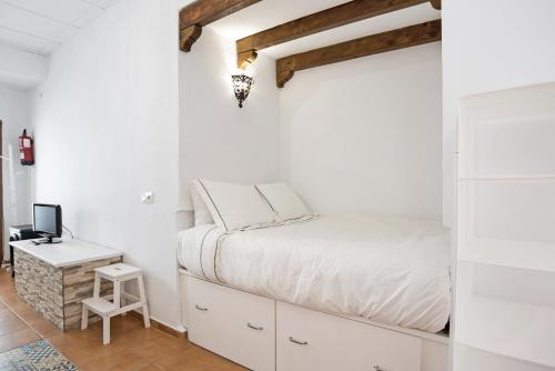 a white bedroom with a bed and a desk at Casa de Berta in Vejer de la Frontera