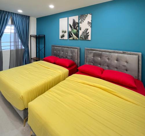 two beds with yellow and red pillows in a bedroom at FuYoke Emerald Avenue @ Brinchang in Cameron Highlands