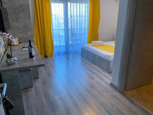 a bedroom with a bed with yellow curtains and a wooden floor at MAV Boutique Villa in Eforie Nord