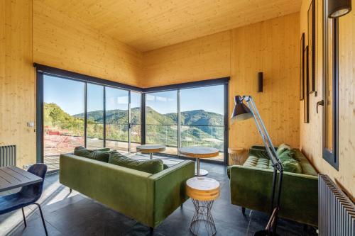 Cette chambre comprend deux canapés verts et une grande fenêtre. dans l'établissement Une des plus belles vues de la Drôme, à Teyssières