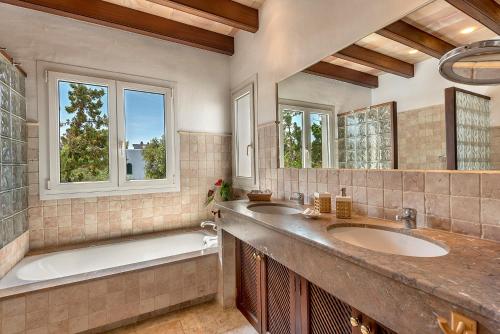a bathroom with two sinks and a tub and two windows at Ca Na Loulou in Cala d´Or