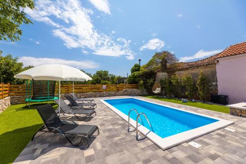 a swimming pool with two chairs and an umbrella at Villa Meri in Gabonjin