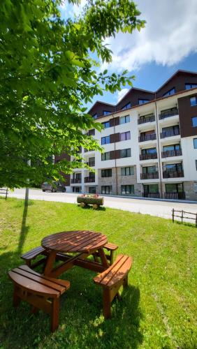 a picnic table and two benches in front of a building at Pinewood ANG luxurious apartment A43, Borovets Gardens in Borovets