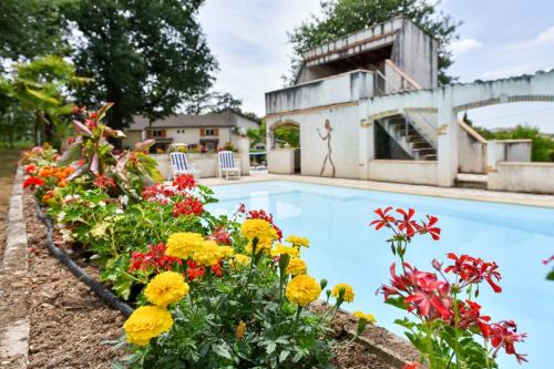 - une piscine fleurie à côté d'une maison dans l'établissement Gîtes les Chênes, à Brens