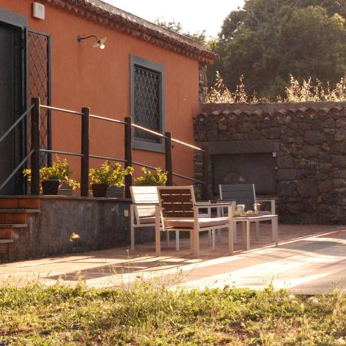 un patio con 2 sedie e un tavolo di fronte a una casa di La casa di Bacco - Etna Country House - Affitto breve a Castiglione di Sicilia