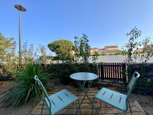 two chairs and a table in a garden at Les Loges de la Mer - Pérols in Pérols