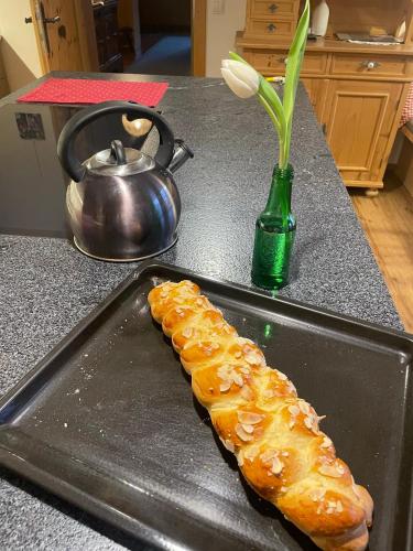 a tray with a loaf of bread on a counter with a vase at Pension Möslehnerhof in Ramsau am Dachstein