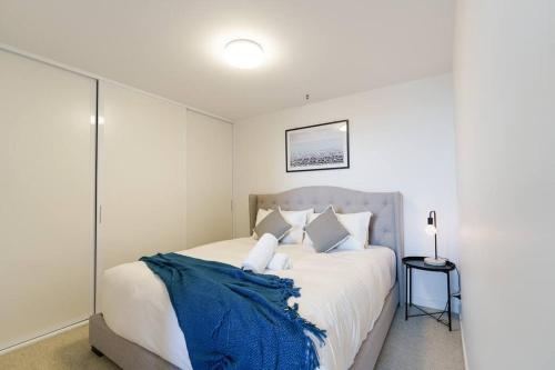 a bedroom with a bed with a blue blanket on it at Modern 1 Bed Opposite Racecourse in Melbourne