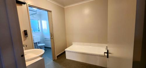 a bathroom with a tub and a toilet and a sink at Acorn Estate Motel in Masterton