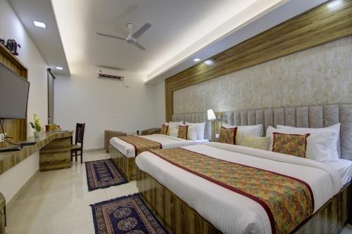 a hotel room with two beds and a flat screen tv at Hotel The Prithvi, Near Delhi Airport in New Delhi