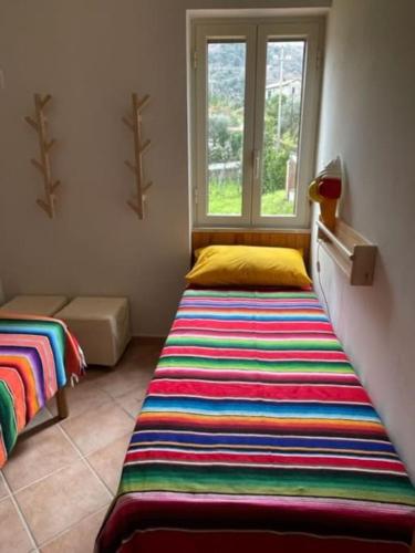 a bedroom with a colorful striped bed and a window at Pink House in Perdifumo