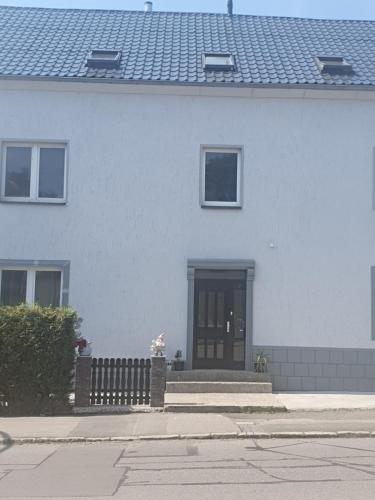 a white house with a black door and a fence at Pension Valentina in Mühlau